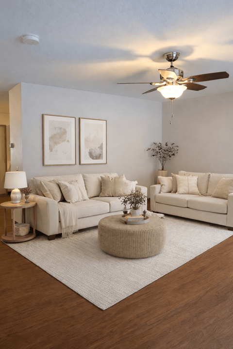 A living room with a white couch, a grey rug, and a wooden floor.