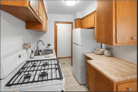 A kitchen with a white stove top oven and a white refrigerator.