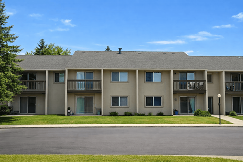 A large apartment building with a parking lot in front.