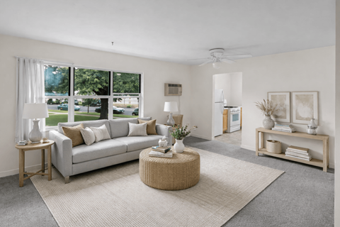A living room with a grey couch, a round wicker table, and a grey rug.