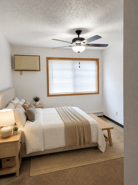 A bedroom with a bed, nightstand, and window.