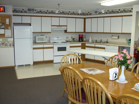 A kitchen with a table and chairs in front of it.