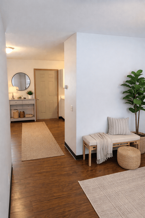 A room with a wooden floor and a white wall with a mirror and a door.