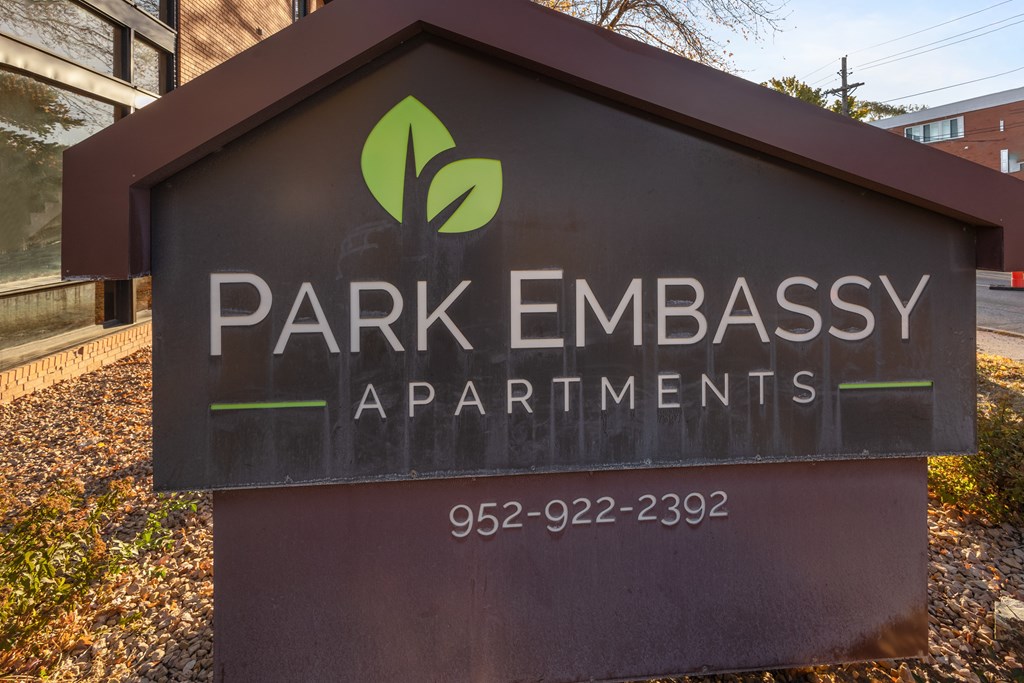A sign for Park Embassy Apartments is shown in front of a building.