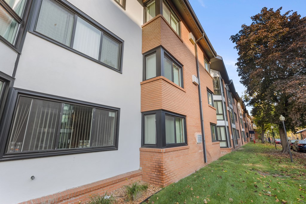 A building with a white and brick facade has windows on the side.