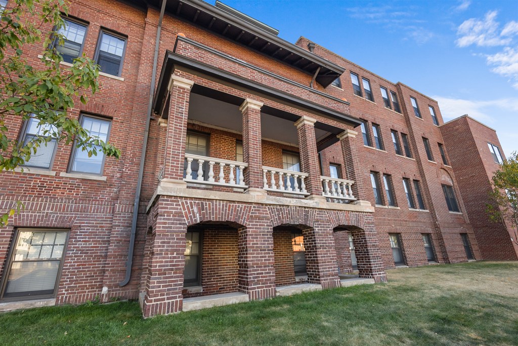 A red brick building with a balcony in the middle.