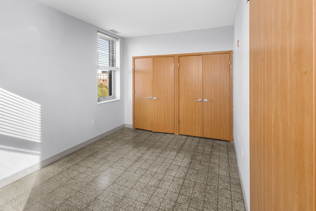 A room with a tiled floor and a window with blinds.