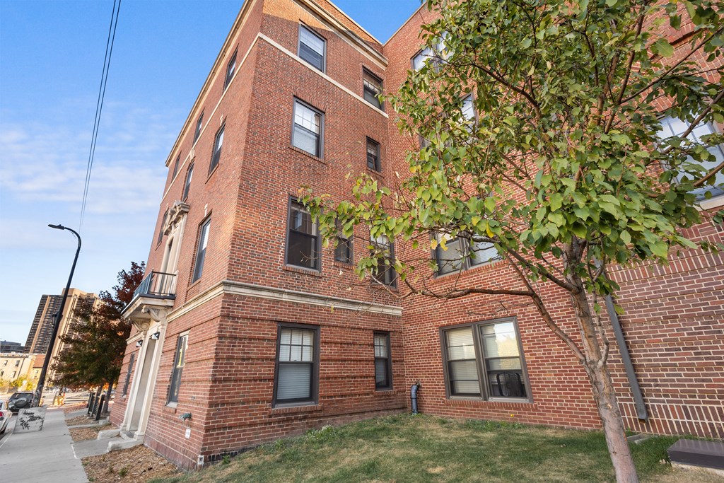 A red brick building with a tree in front.
