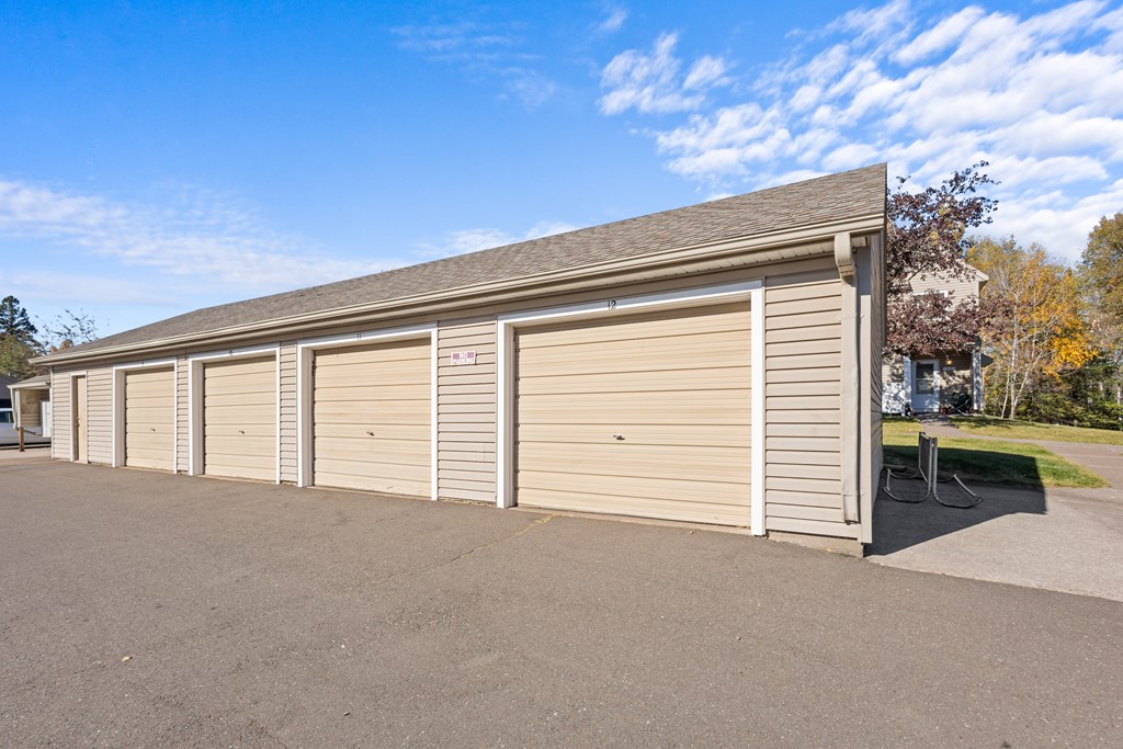 A long building with a grey roof and tan garage doors.
