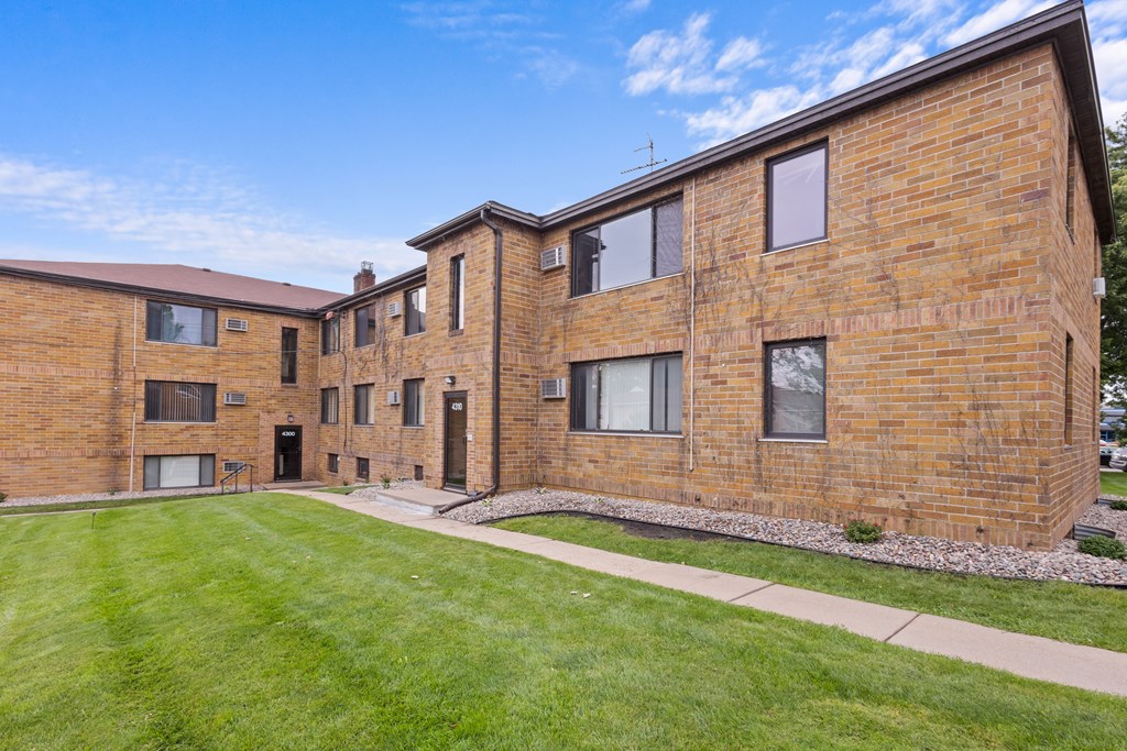 A brick building with a green lawn in front.
