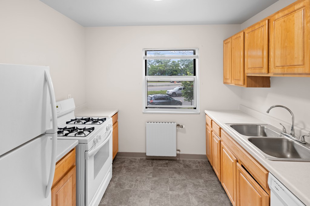 A kitchen with white appliances and wooden cabinets.