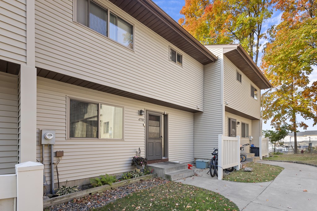 A beige house with a brown roof and a grey front porch.