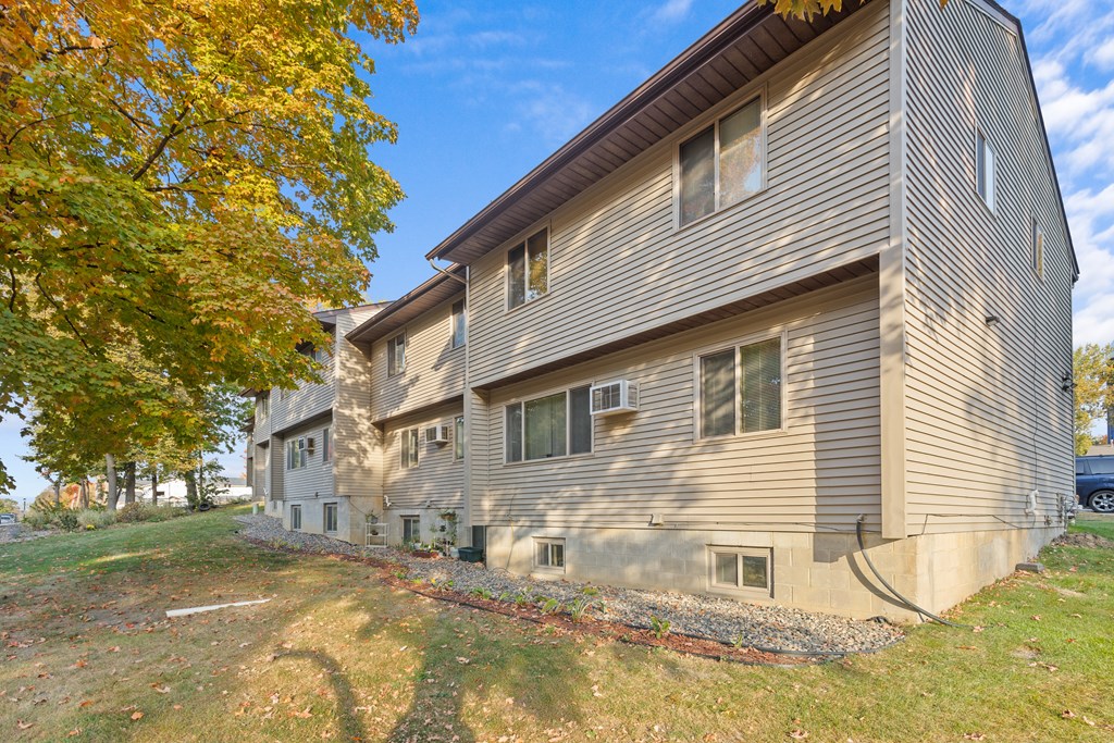 A house with a grey siding and a brown roof with a tree in the front.