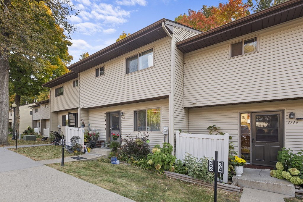 A house with a grey siding and a black door is shown.