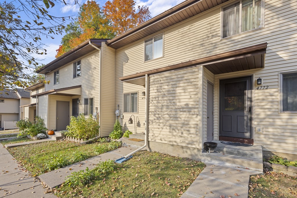 A beige house with a brown door and a small front yard.