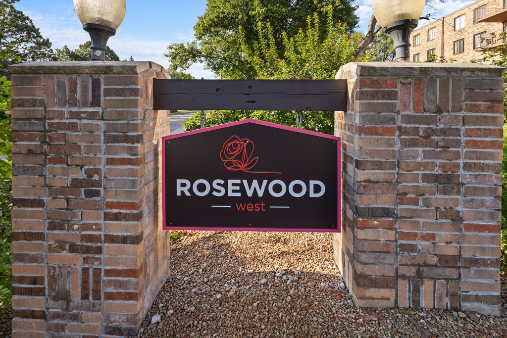 A sign that says Rosewood West is displayed on a brick wall.