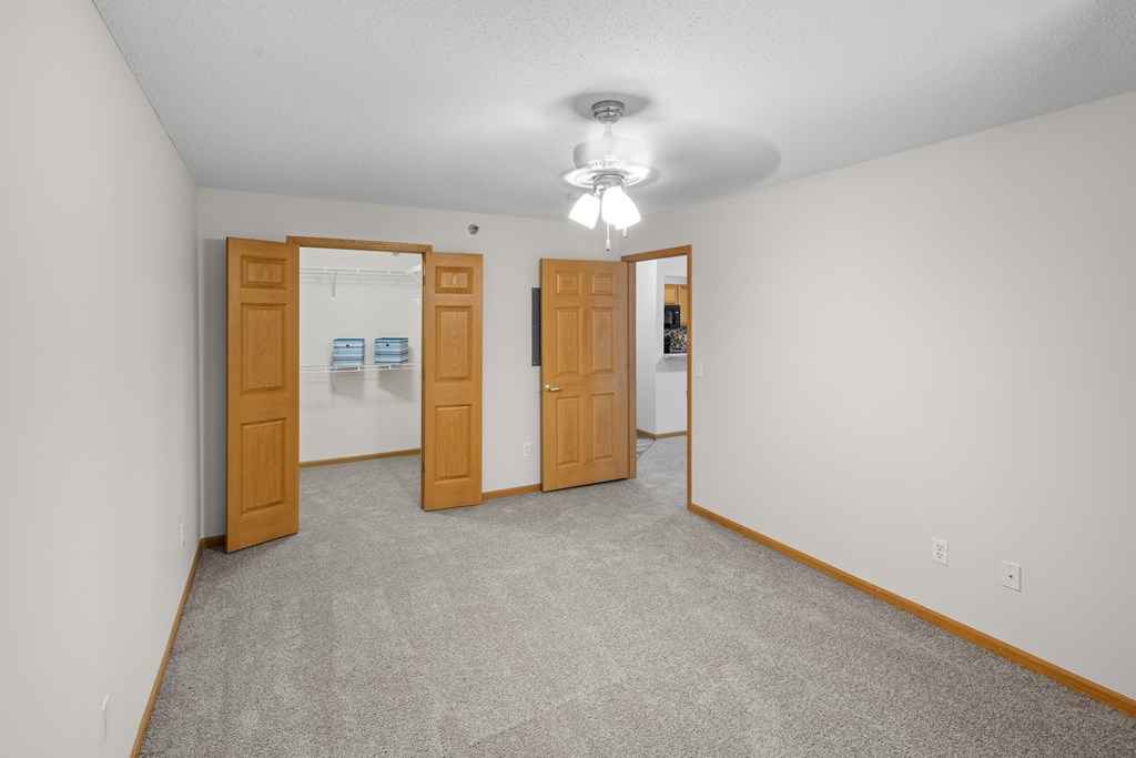 A room with carpeted floor and two wooden doors.