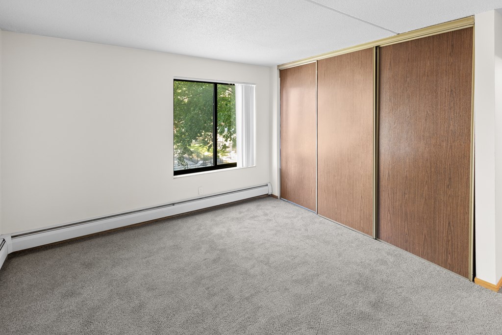 A room with a window and a brown wardrobe.