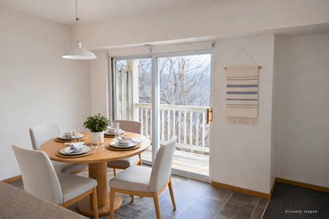 A dining room with a table set for two and a view of a deck outside.