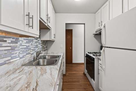 A kitchen with white cabinets and a marble countertop.