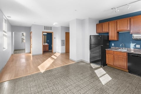 A kitchen area with a black refrigerator and wooden cabinets.