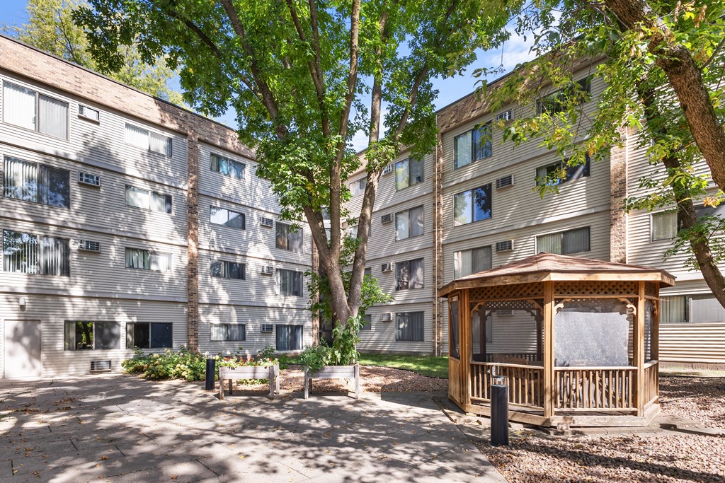 A gazebo sits in the middle of a courtyard between two apartment buildings.