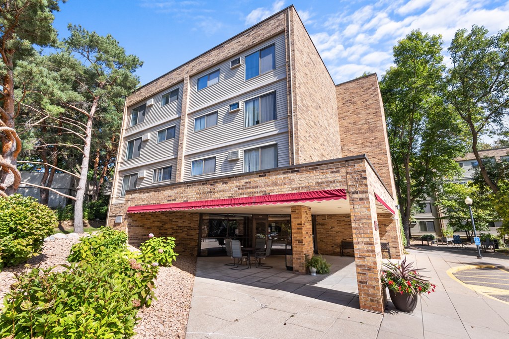 A building with a red awning and a parking lot in front.