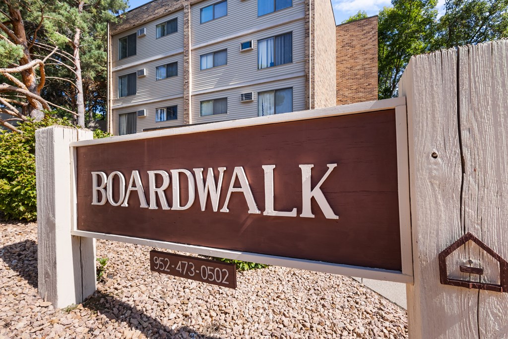 A brown sign that says Boardwalk in front of a building.