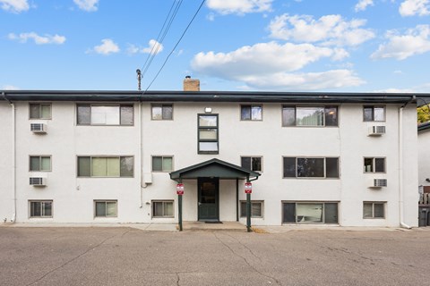 A white building with a green awning and a red sign on it.
