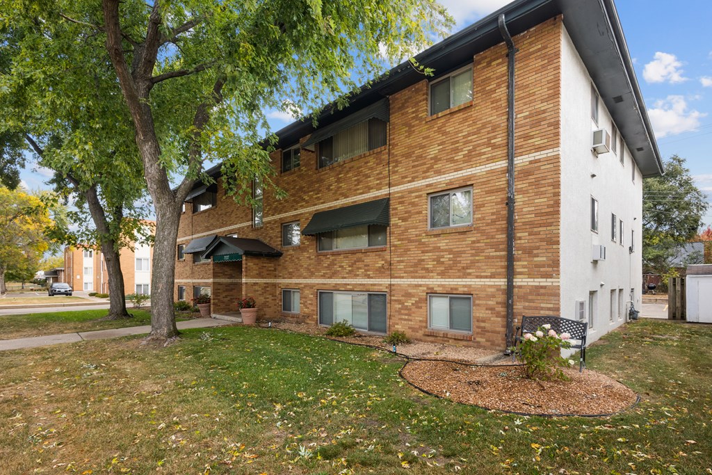 A brown and white building with a tree in front.