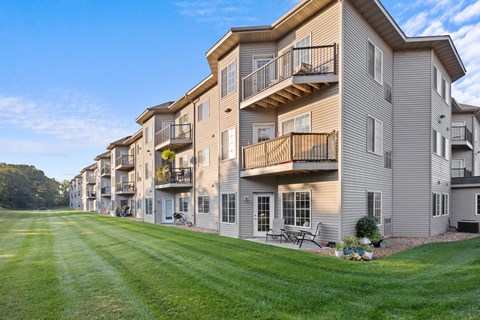 A row of apartment buildings with balconies and green lawns.