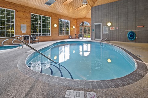 A round indoor swimming pool with a glass wall surrounding it.