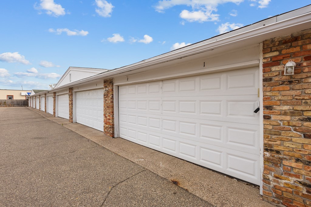 a row of garages with white garage doors on a brick building