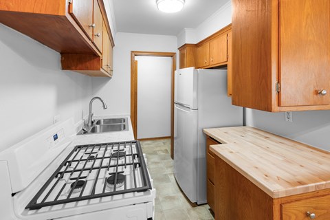 A kitchen with a white stove top oven and a white refrigerator.