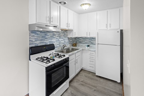 A kitchen with a white stove and white cabinets.