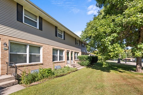 a side view of a house with a lawn and trees