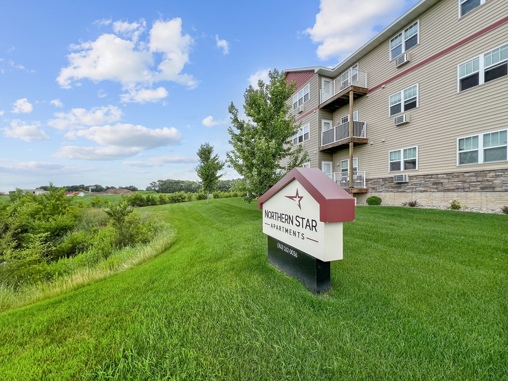 A sign for Northern Star Apartments stands in a grassy field.