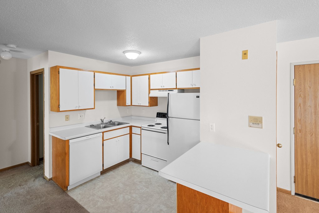 an empty kitchen with white appliances and wooden cabinets