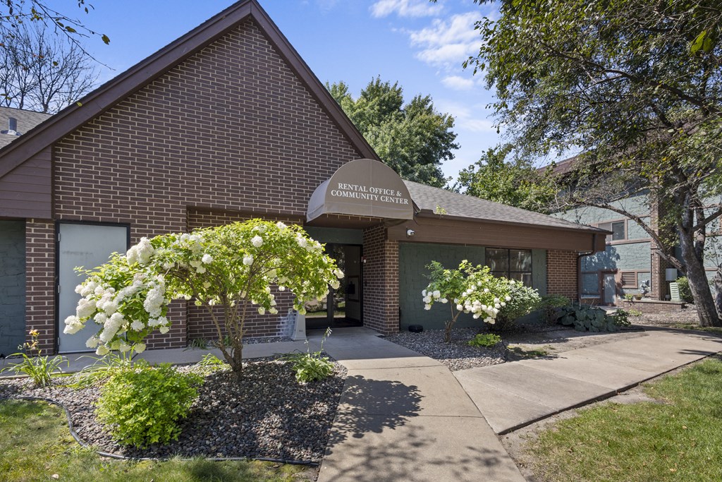 the front of a brick building with a sidewalk and trees