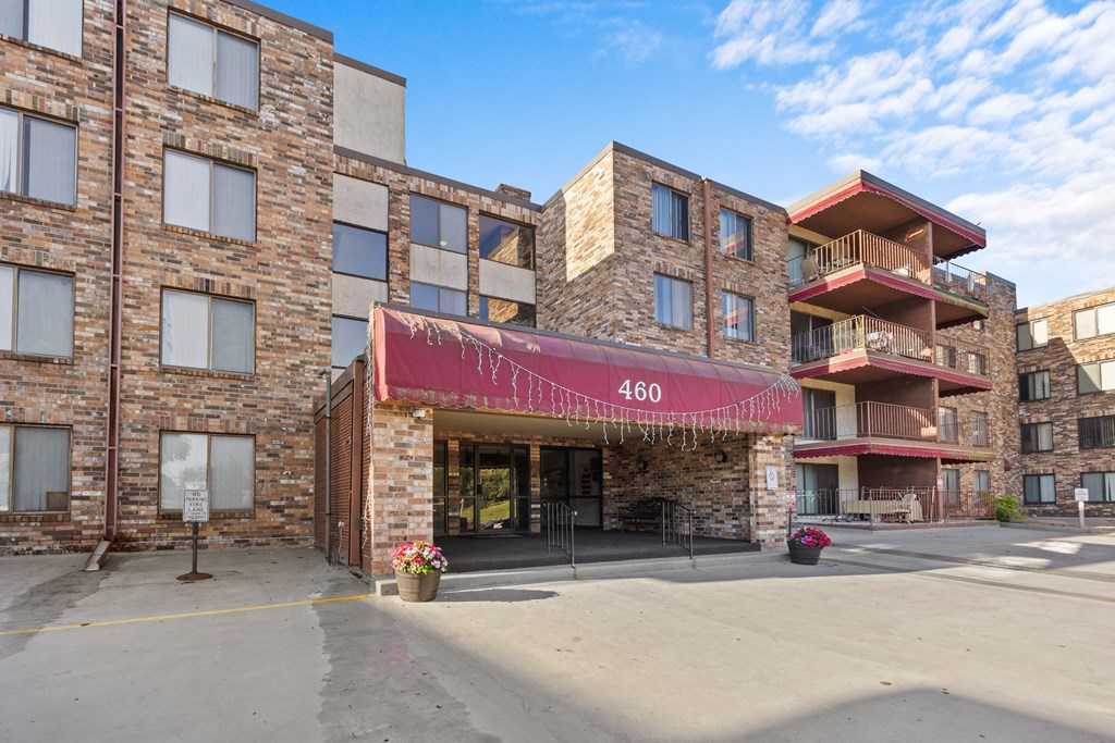 an apartment building with a red awning and a street in front