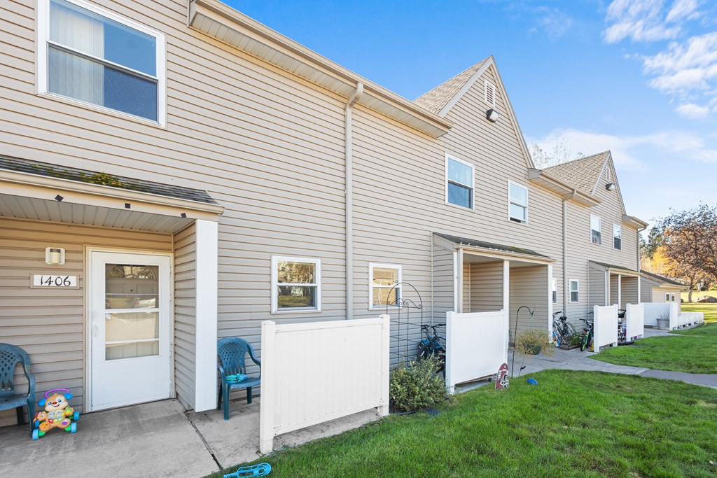 A residential building with a white fence and a blue chair in front.