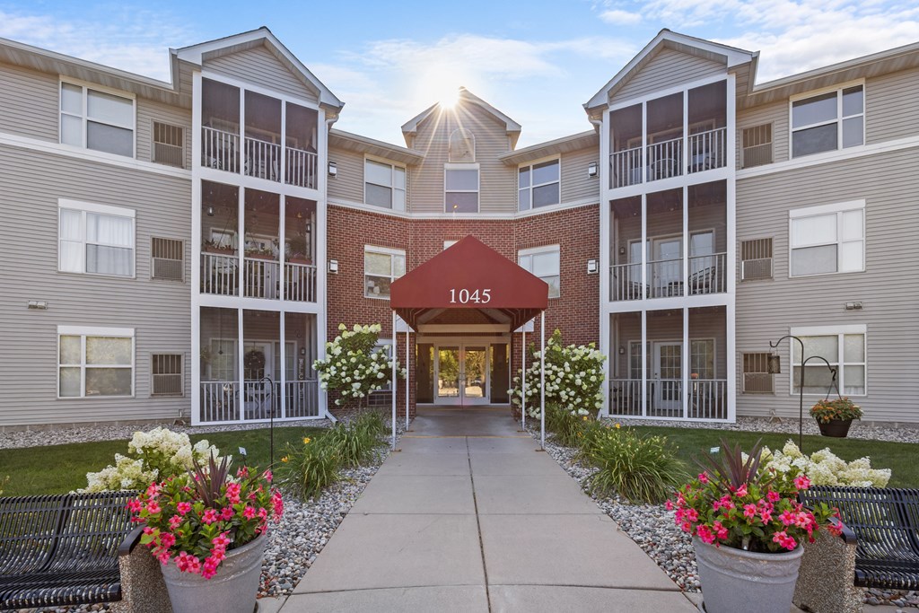 an exterior view of an apartment building with a walkway and flowers