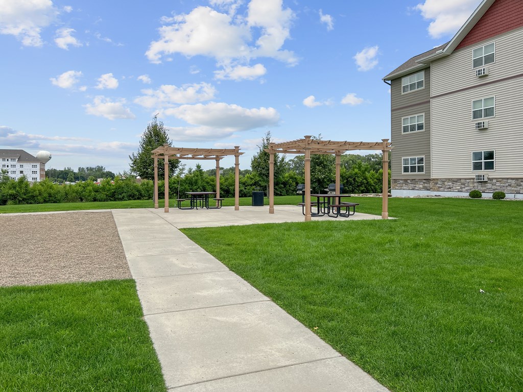 A park with a walkway, benches, and a wooden structure.