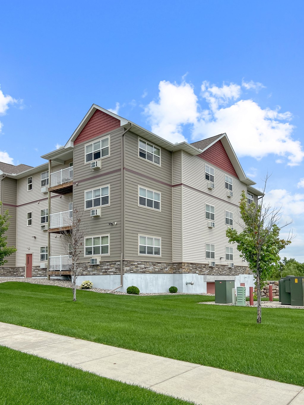 A large apartment building with a red roof and a tree in front.