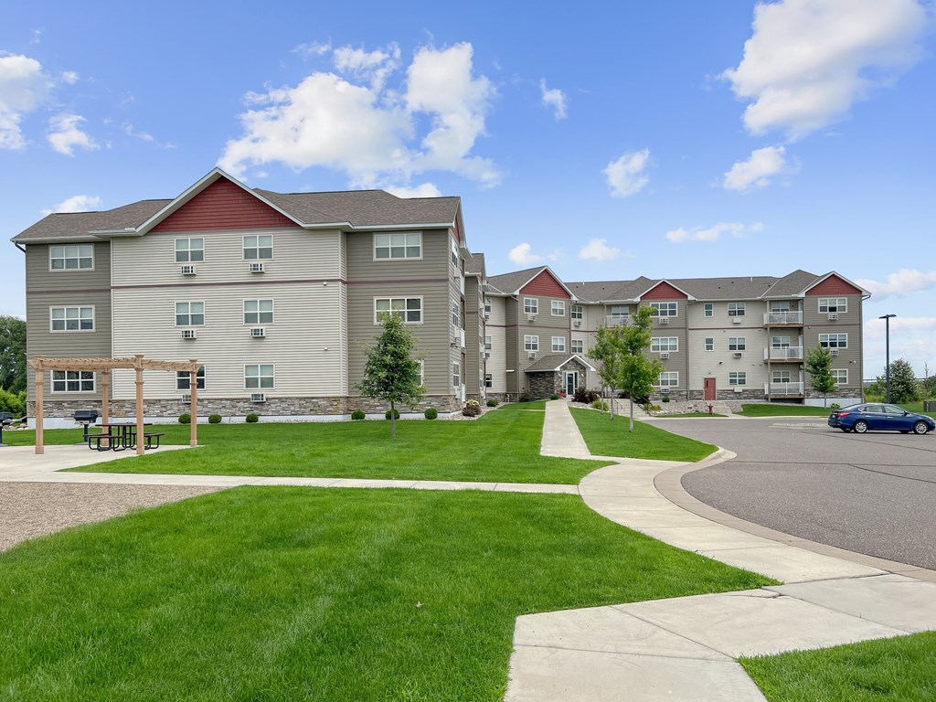 A large apartment complex with a grassy courtyard and a walking path.