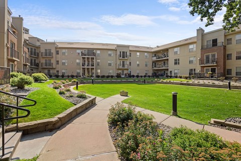 A sunny day at a well-maintained apartment complex with a green lawn and walking paths.