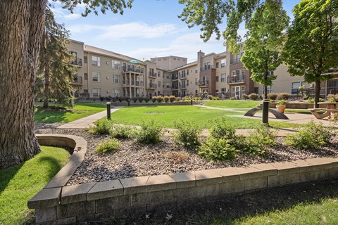 a courtyard with trees and grass in front of an apartment building
