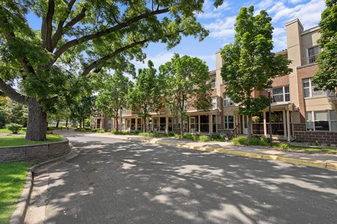 A tree-lined street in front of a brick apartment building.