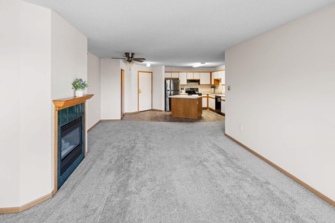 A living room with a fireplace and a grey carpet.
