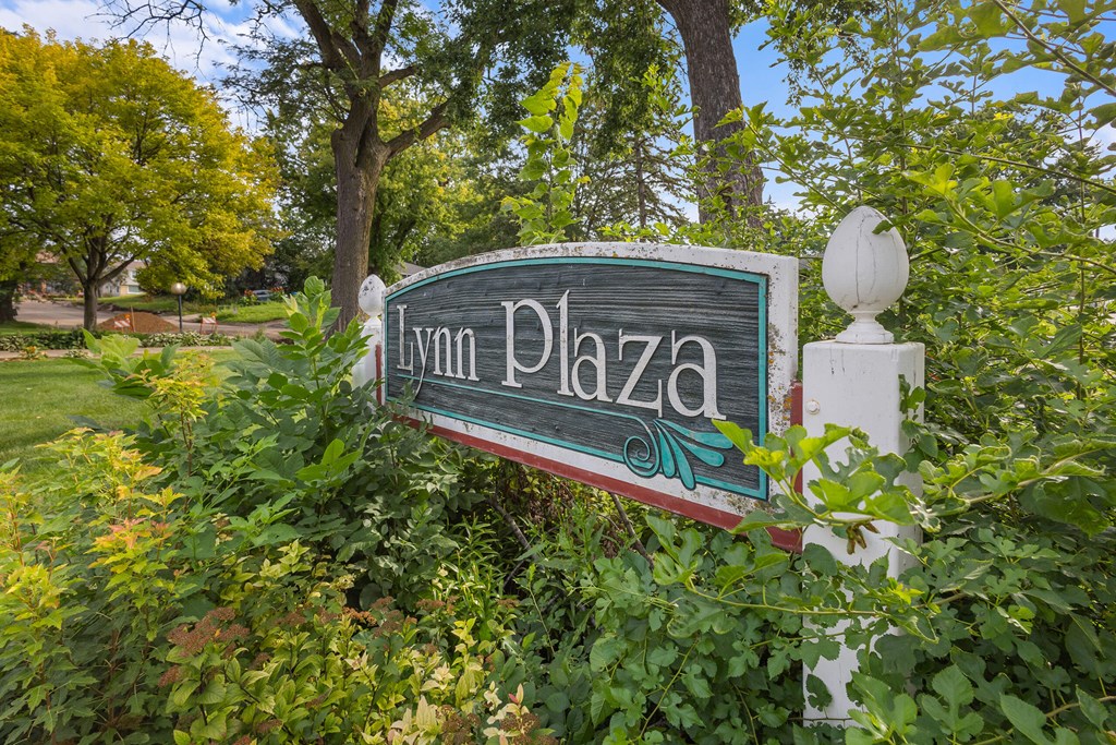A sign that says Lyn Plaza is surrounded by greenery.